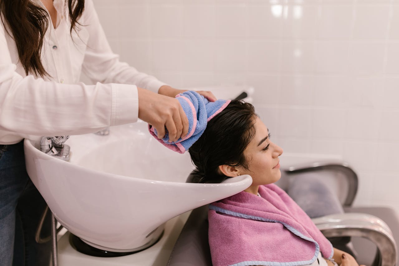 Mastering the First Impression: Your intriguing post title goes here A woman enjoys a relaxing hair wash at a modern hair salon, emphasizing self-care and pampering.